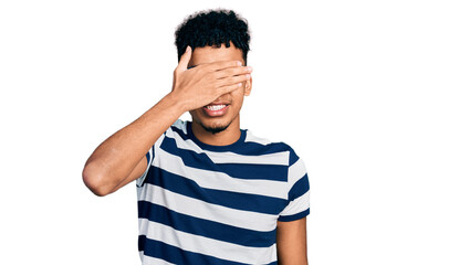 Fototapeta premium Young african american man wearing casual clothes and glasses smiling and laughing with hand on face covering eyes for surprise. blind concept.