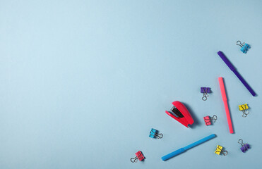 stationery felt-tip pens pins stapler on blue background. Flatlay.