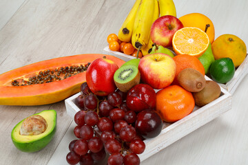 Delicious fresh fruit with grapes, tangerine, papaya, banana, avocado, orange, kiwi