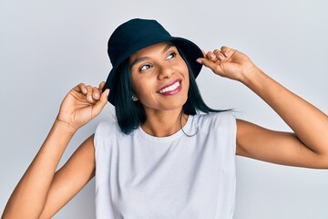Young african american woman wearing fashion hat smiling looking to the side and staring away thinking.