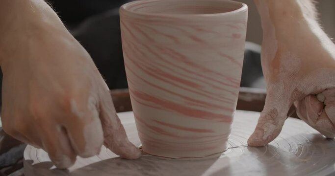 Close up view: potter separates the molded nerikomi pot from the potter's wheel, pottery workshop, ceramics craftsmanship, 4k 60p Prores HQ 10 bit