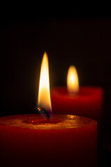 Two red lighted candle on a black background. Two lights in the dark.