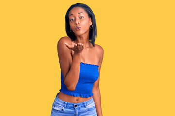 Young african american woman wearing casual summer clothes looking at the camera blowing a kiss with hand on air being lovely and sexy. love expression.