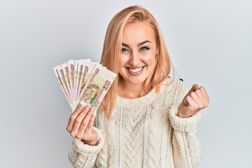 Beautiful caucasian woman holding 100 russian ruble banknotes screaming proud, celebrating victory and success very excited with raised arm