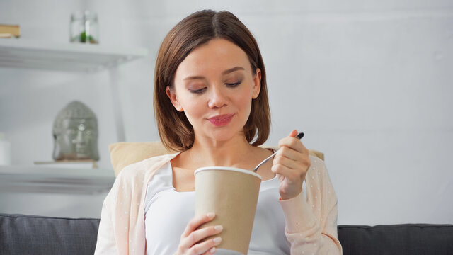 Young Pregnant Woman Holding Ice Cream And Spoon At Home