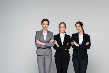 Smiling managers looking at camera isolated on grey with copy space