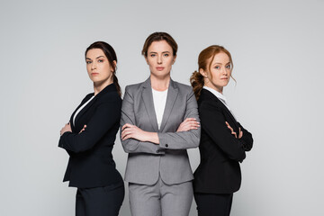 Businesswomen with crossed arms looking at camera isolated on grey