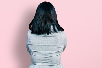 Young hispanic plus size woman wearing winter scarf standing backwards looking away with crossed...
