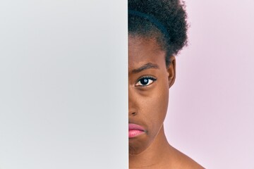 Young african american girl holding blank empty banner over half face depressed and worry for...