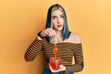 Young modern girl holding honey clueless and confused expression. doubt concept.