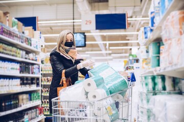 Woman with face mask buying toilet paper in supermarket during virus epidemic.