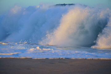 Ondas quebrando no mar na Praia de Piratininga, Niterói no Rio de Janeiro. Morro ao fundo. Fim de tarde de verão.