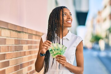 Young african american woman smiling happy counting norwegian 50 krona banknotes at the city.
