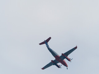 in the gray sky flies the propeller transport plane