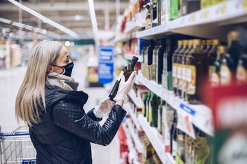 A woman in a face mask buys groceries in supermarket.