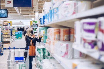 Woman with face mask and gloves on shopping at supermarket.