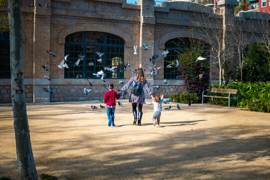 Madre con sus hijos corriendo hacia las palomas