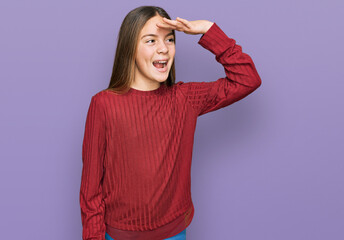 Beautiful brunette little girl wearing casual sweater very happy and smiling looking far away with hand over head. searching concept.