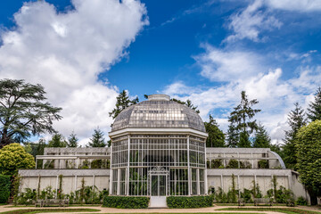The glass house against a cloudy blue sky at the Albert Kahn gardens in Paris France.
