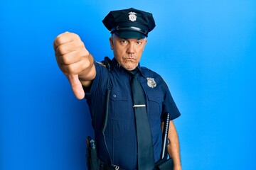 Handsome middle age mature man wearing police uniform looking unhappy and angry showing rejection and negative with thumbs down gesture. bad expression.