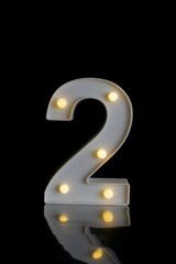 Number 1 (one) made of white plastic, illuminated, in focus, with balls of lights, with a black background and on a mirrored black floor