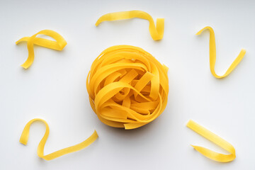 Italian pasta. Uncooked tagliatelle nest on white background
