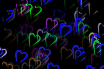 Defocused image of multicolored silhouettes of hearts on an abstract background. Dark background, blur bokeh.