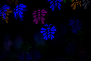 Defocused image of multicolored bees on an abstract background. Dark background, blur bokeh.