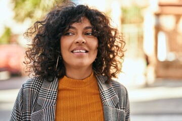 Young hispanic businesswoman smiling happy standing at the city.