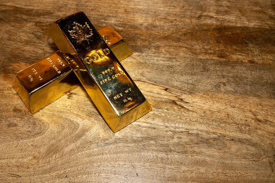 Two Solid Gold Bars On A Wooden Table