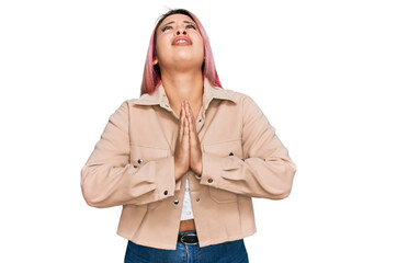 Hispanic woman with pink hair wearing casual clothes begging and praying with hands together with...