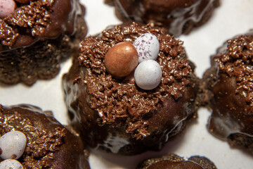 A selection of Easter Chocolate nest Cakes topped with three little chocolate mini eggs on a white plate