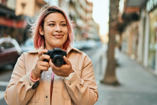 Young hispanic girl smiling happy using reflex camera at the city.