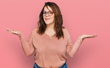 Young plus size woman wearing casual clothes and glasses clueless and confused expression with arms...