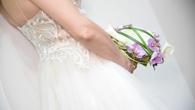 A bride holds in her hand a Bouquet of purple orchids and white flowers Bouquet of wedding flowers 