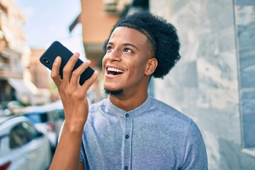 Fototapeta na wymiar Young african american man smiling happy sending audio message using smartphone at the city.