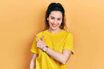 Young hispanic woman wearing casual clothes smiling cheerful pointing with hand and finger up to the side