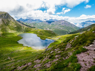 Ibón de Escalar, que es una laguna glaciar en los Pirineos españoles, muy cerca de la frontera francesa; con las grandes praderas de montaña y las altas cumbres al fondo