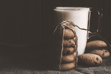 Stack of chocolate homemade cookies on black background with glass of milk on burlap tablecloth - Powered by Adobe