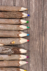 Colored crayons made of untreated wood with real tree bark on wooden board for students, artists and nature lovers