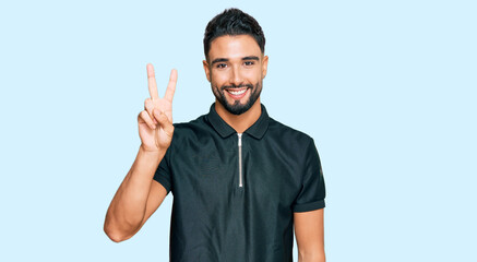 Fototapeta premium Young man with beard wearing sportswear showing and pointing up with fingers number two while smiling confident and happy.