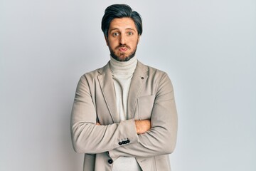 Young hispanic man with arms crossed gesture puffing cheeks with funny face. mouth inflated with air, catching air.