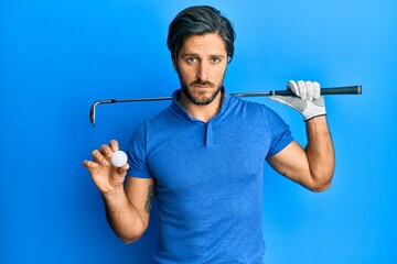 Young hispanic man holding golf ball depressed and worry for distress, crying angry and afraid. sad...