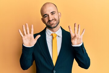 Young hispanic man wearing business suit and tie showing and pointing up with fingers number nine while smiling confident and happy.