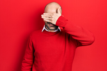 Young bald man wearing casual clothes and glasses smiling and laughing with hand on face covering eyes for surprise. blind concept.