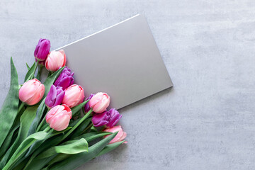 A gray laptop and a bouquet of tulips on a gray concrete background. Сopyspace