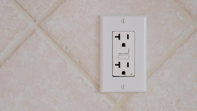Unplugging an electrical usb cord and charger plug from wall outlet. Cell phone power adapter brick and cord in GFCI wall plug.