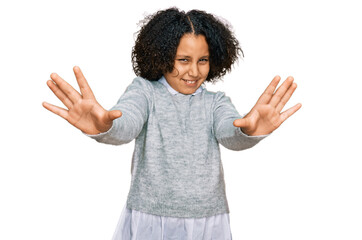 Young little girl with afro hair wearing casual clothes afraid and terrified with fear expression stop gesture with hands, shouting in shock. panic concept.