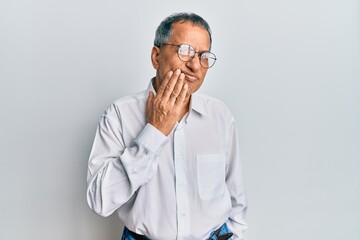 Middle age indian man wearing casual clothes and glasses touching mouth with hand with painful expression because of toothache or dental illness on teeth. dentist