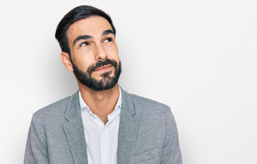 Young hispanic man wearing business clothes smiling looking to the side and staring away thinking.